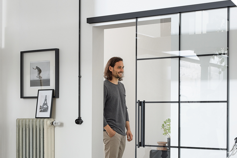 Moderne Lofttür mit schwarzem Metallrahmen und Glaseinsätzen in einem hellen Wohnraum.