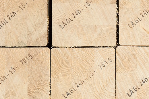 Gestapelte Brettschichtholzbalken mit sichtbarer Jahresringstruktur und Markierungen für den Holzbau.
