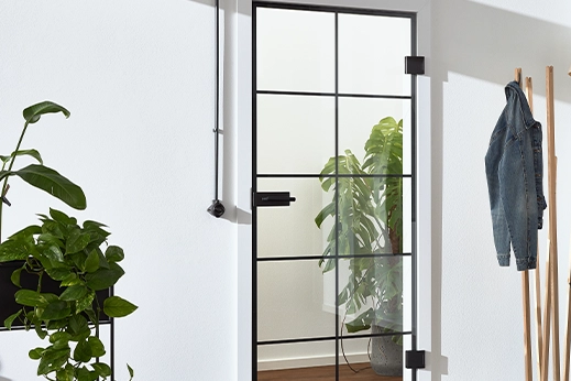 Loft-Glastür mit schwarzem Gitterrahmen in heller Garderobe.