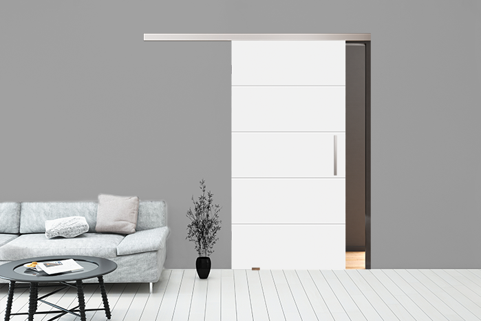 Moderne weiße Schiebetür in grauer Wand, neben grauem Sofa mit Beistelltisch und Dekopflanze.