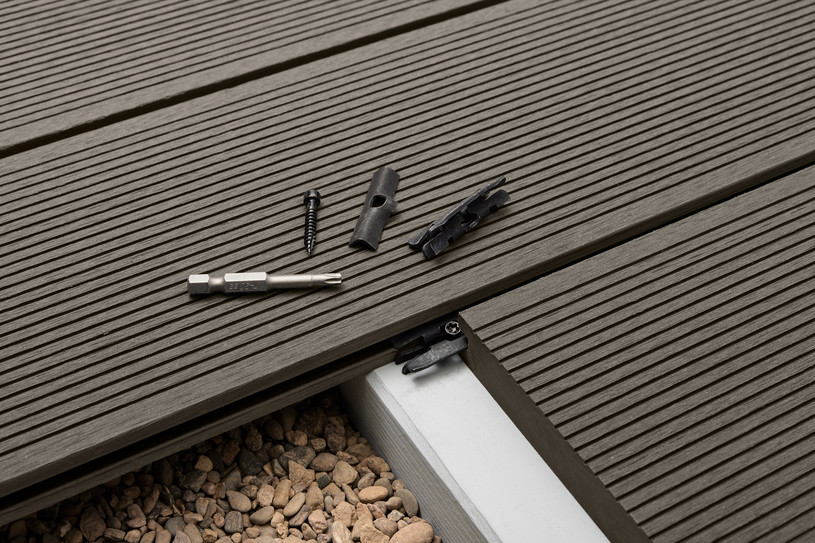 Graue Terrassendielen mit verdeckter Unterkonstruktion, Werkzeug und Zubehör auf einer modernen Holzterrasse.
