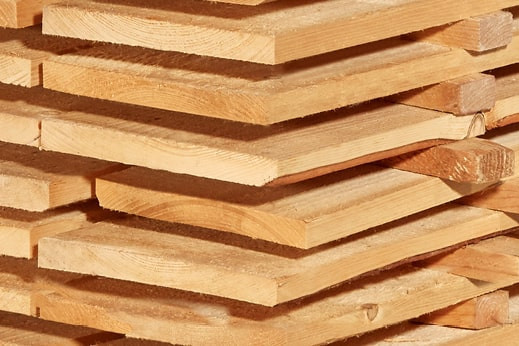 Gestapelte Schalbretter aus Holz mit sägerauer Oberfläche, ideal für den Bau- und Konstruktionsbereich.
